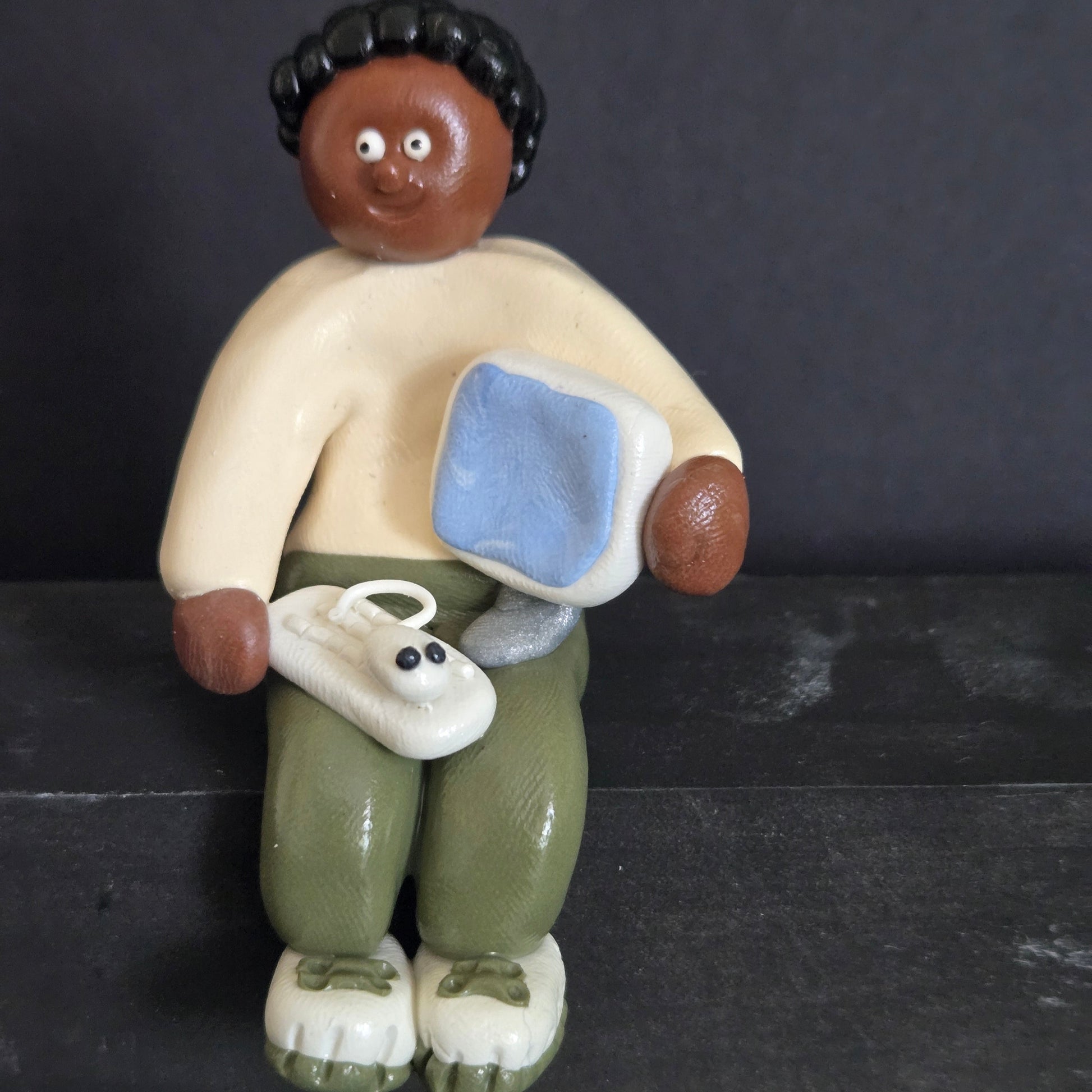 Small figurine of a person watching TV with a dog on a dark background