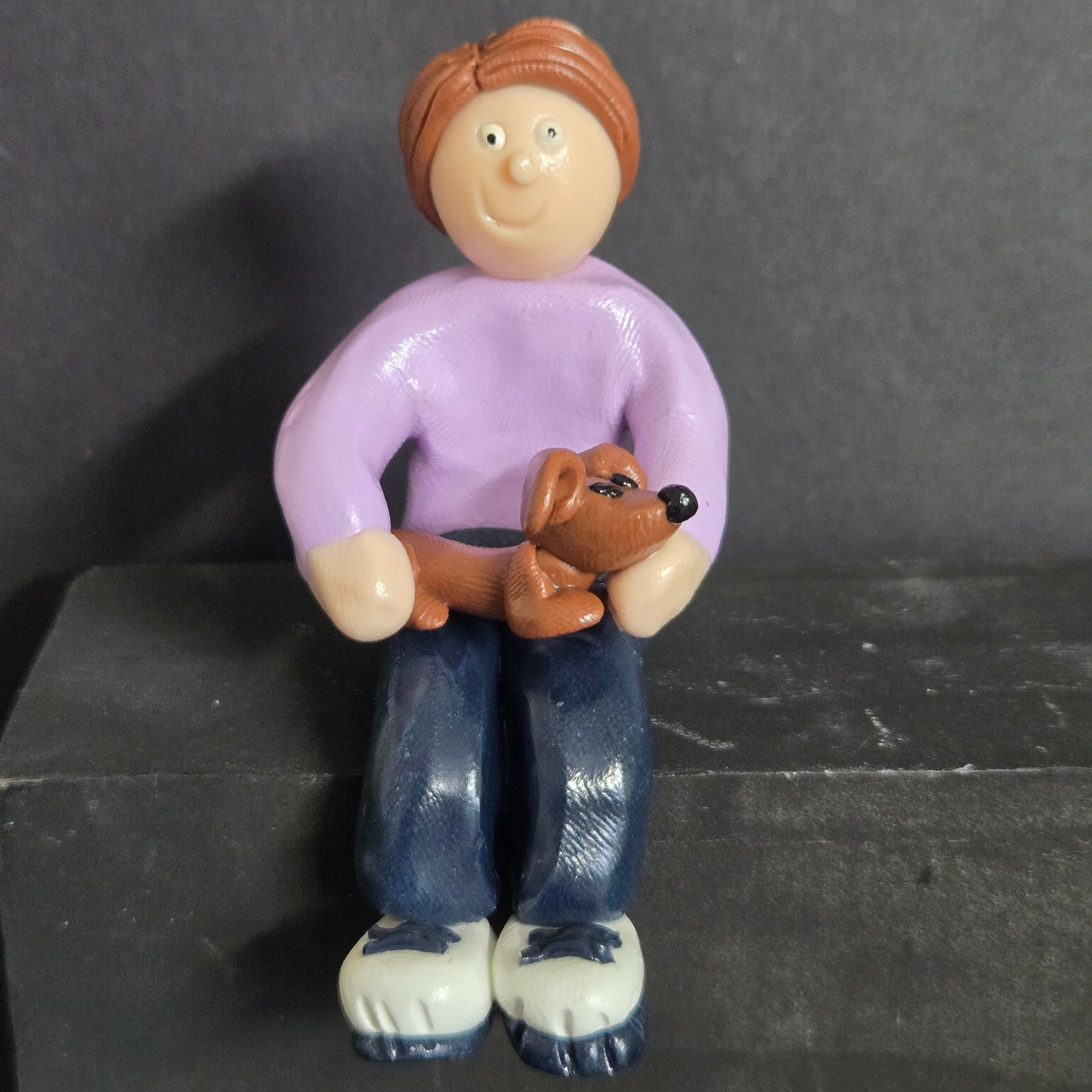 Small figurine of a person with a dog on a leash against a dark background