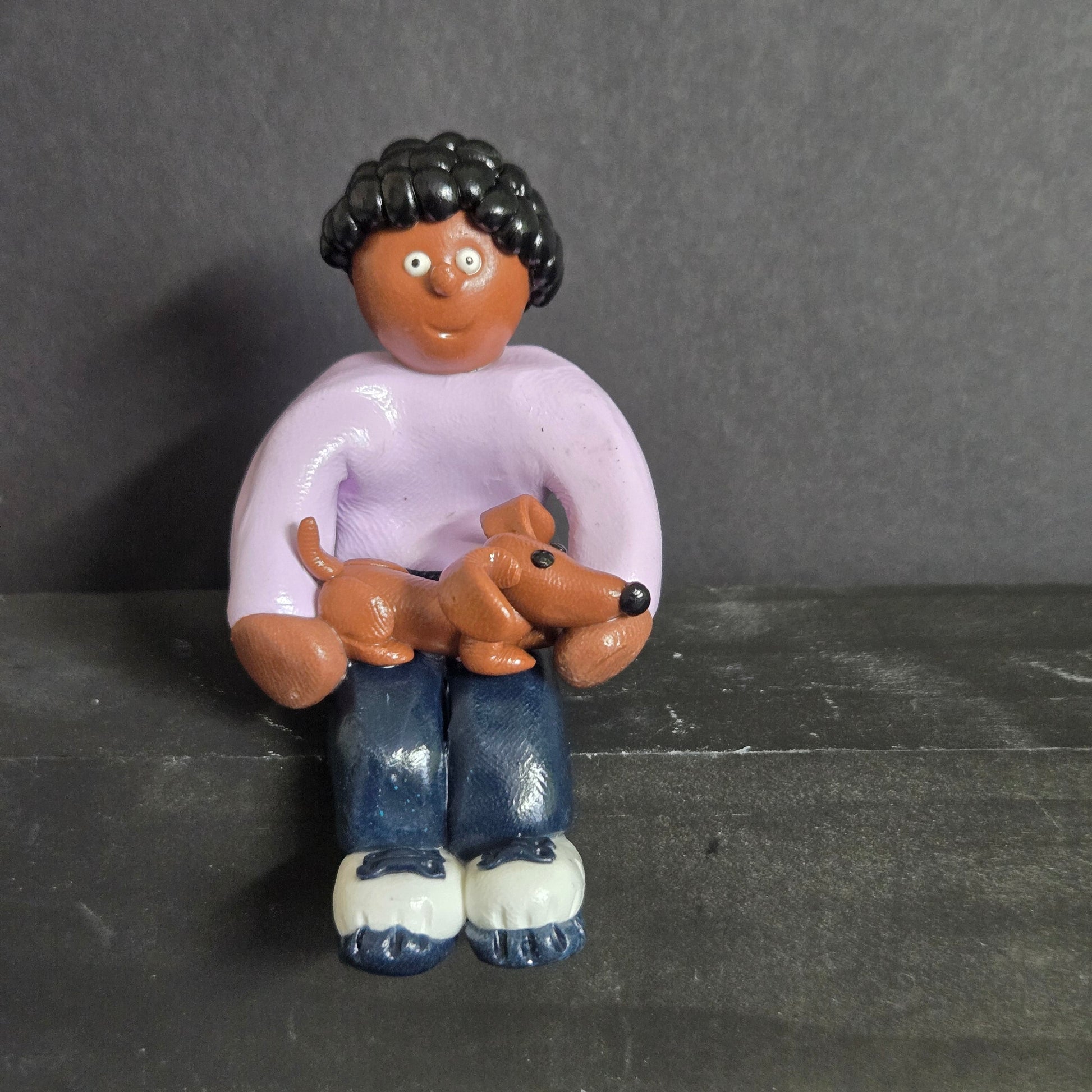 Decorative figurine of a person with a dog on a gray background
