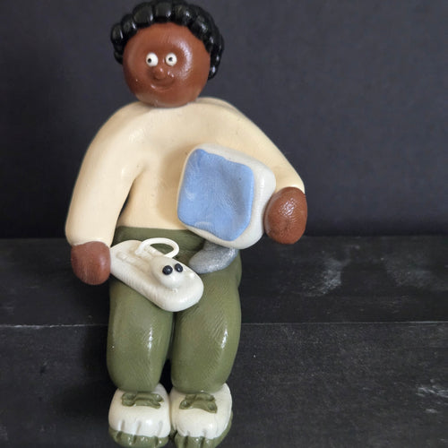 Small figurine of a person watching TV with a dog on a dark background